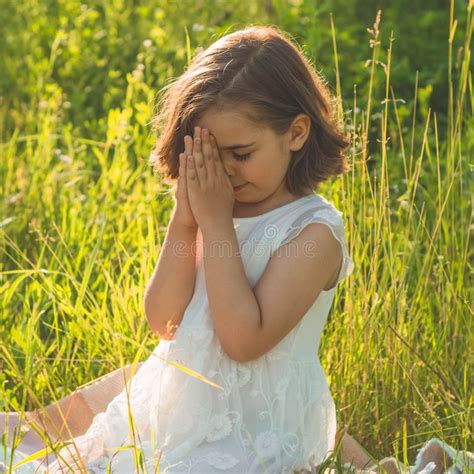 Little Girl Closed Her Eyes Praying In A Field During Beautiful Sunset