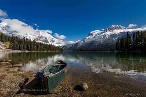 A Boat Sitting On The Shore Of A Mountain Lake