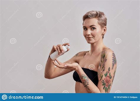 Portrait Of Beautiful Tattooed Woman With Pierced Nose And Short Hair Holding Plastic Bottle