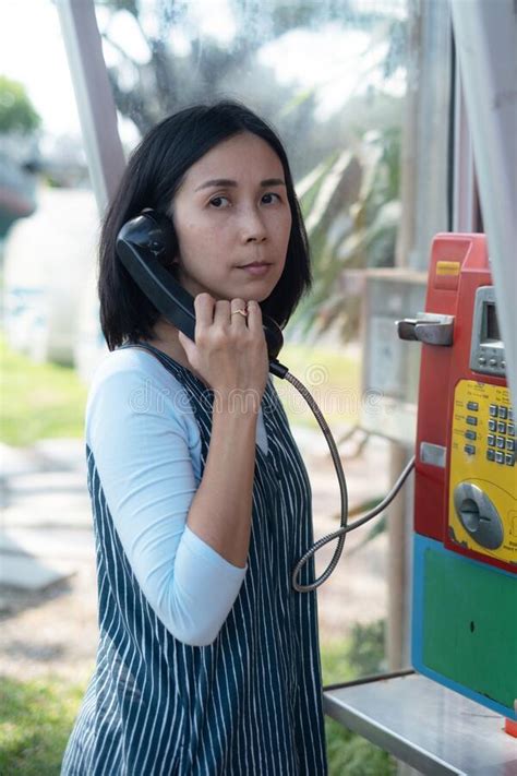 Woman Using Oldstyle Public Pay Phone In Telephone Booth Stock Photo