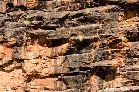Image Of Shot Of Rocky Cliff Face With Layered Orange And Dark Rock