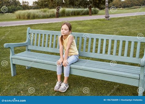 Cute Little Girl Sitting On A Wooden Bench In Park Child Spending Time