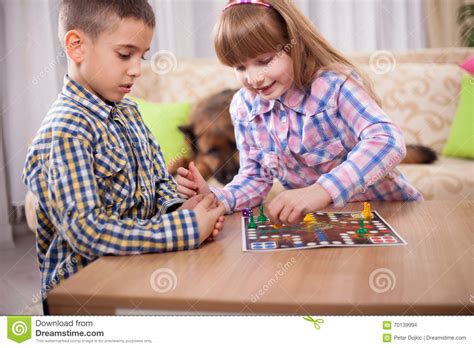 Children Playing Board Game Ludo At Home On The Table Stock Photo