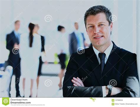 Happy Businessman Standing In Front Of His Colleagues In Office Stock