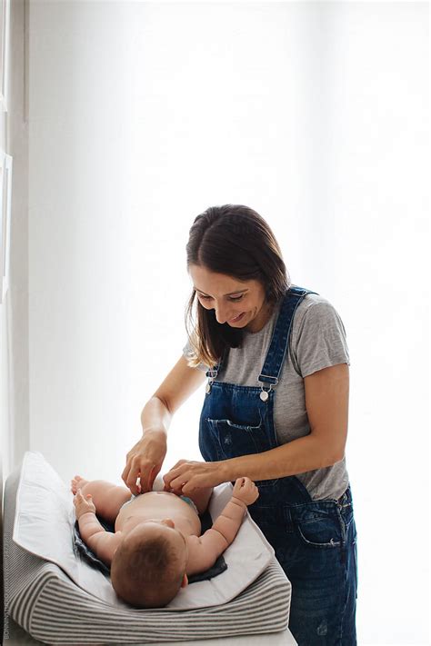 Portrait Of A Young Mother Giving Baby A Diaper Change By Stocksy