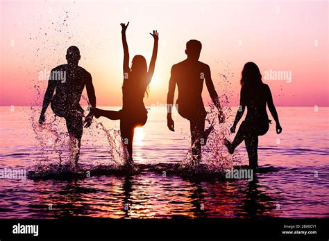 Happy Friends Splashing Water On Tropical Beach At Sunset Group Of