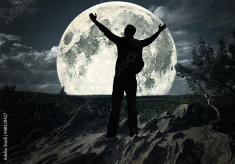 Man Standing On The Top Of Mountain Looking At The Moon Stock Photo