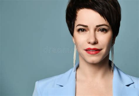 Smiling Short Haired Brunette Woman In Blue Business Suit And Hat Sits