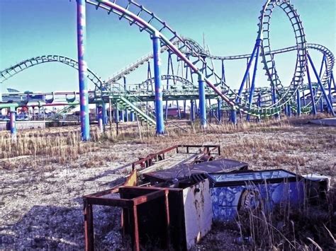 An Abandoned Amusement Park With Roller Coasters In The Background
