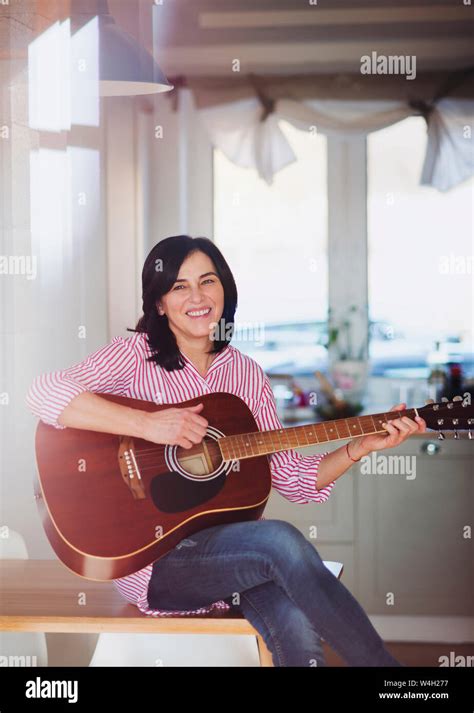 Portrait Of Smiling Mature Woman Playing Guitar At Home Stock Photo Alamy