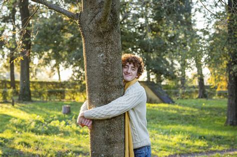 Smiling Young Man Hugging Tree At Park Stock Photo
