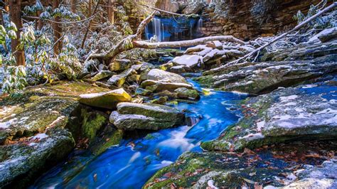 Waterfall Stream Between White Snow And Algae Covered Stones Trees In