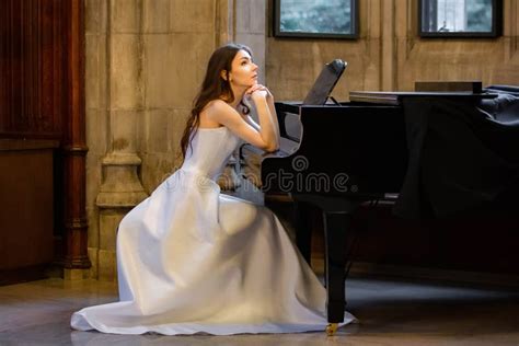 Portrait Of A Beautiful Girl Wearing White Wedding Dress At The Piano