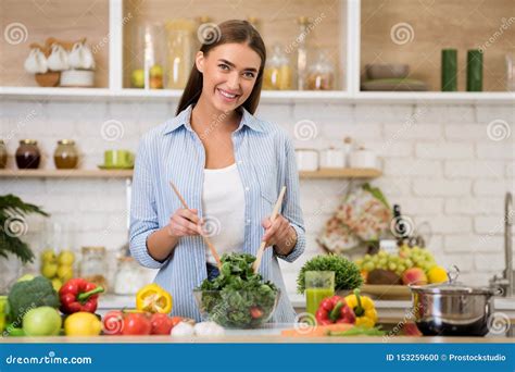 Happy Woman Cooking Dinner Mixing Fresh Salad In Kitchen Stock Photo