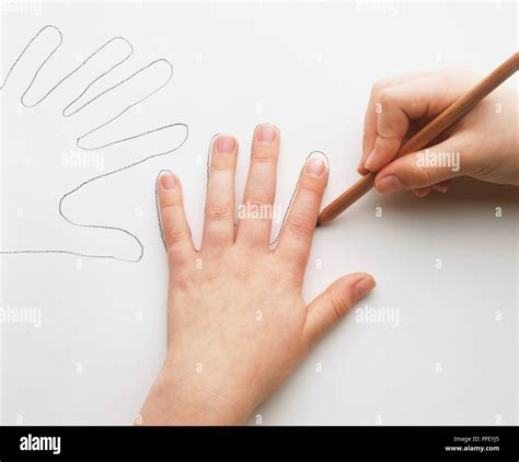 Child Using Pencil To Draw Around Fingers Of Left Hand Stock Photo Alamy