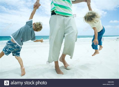 Man Picking Up Son And Daughter By Arms On Beach Stock Photo Alamy