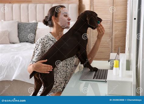 Young Woman Getting Distracted By Her Dog While Working With Laptop In