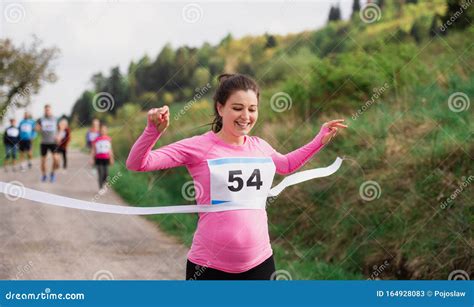 Pregnant Woman Runner Crossing Finish Line In A Race Competition In