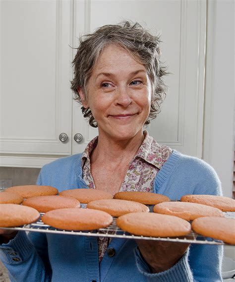 An Older Woman Holding A Tray Full Of Donuts