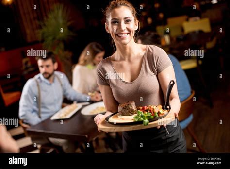 Cute Young Waitress Holding A Wooden Plate With Beef Steak In The