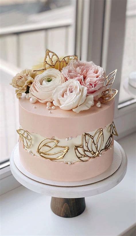 A Three Tiered Cake With Pink And White Flowers On The Top Is Next To A