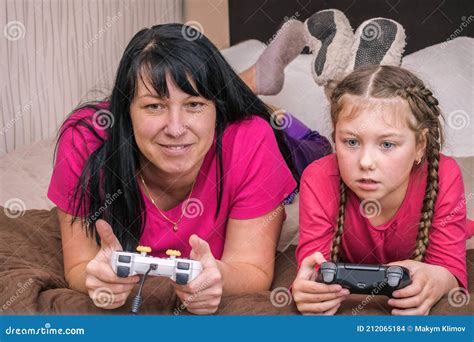 Mother And Daughter Play Computer Games Using Gamepads A Woman And A