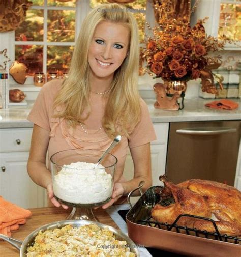 A Woman Standing In Front Of A Large Pan Filled With Food Next To A Turkey