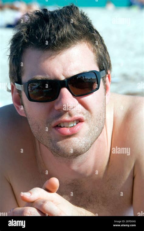 Close Up Of A Young Man Lying On The Beach With His Hands Clasped