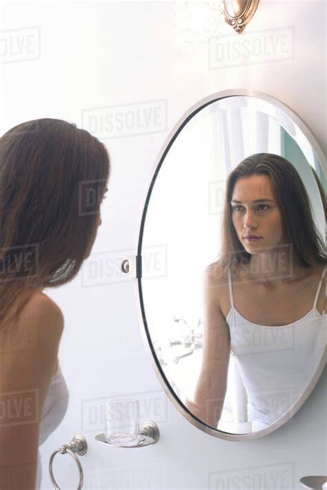 Woman Looking At Self In Bathroom Mirror Stock Photo Dissolve