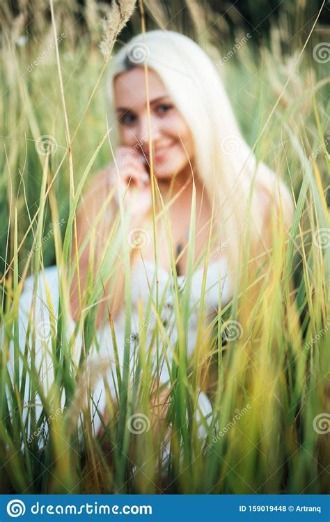 Smiling Girl Blonde Sitting In Tall Grass In Background Blurred Stock