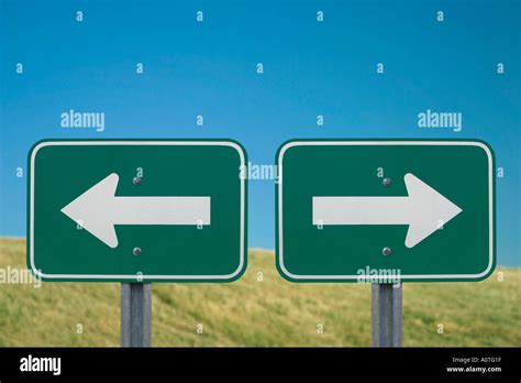 Two Road Signs Each With An Arrow Pointing In The