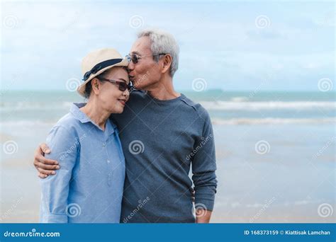 Kissing Moment Of Asian Couple Senior Elder Retirement Resting At Beach Honeymoon Stock Image