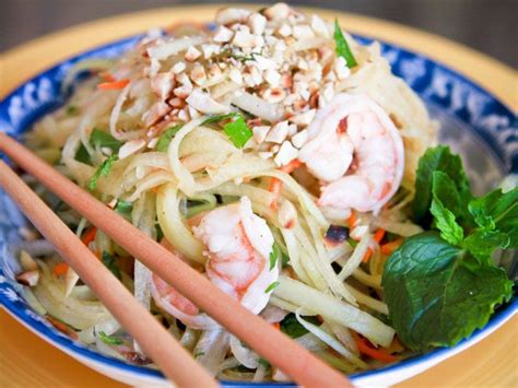 A Blue And White Bowl Filled With Noodles And Shrimp Next To Two Chopsticks