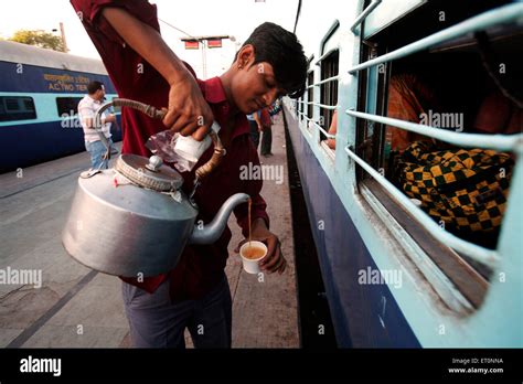 Indian Railway Tea Vendor Pouring Tea From Aluminium Kettle Into Stock
