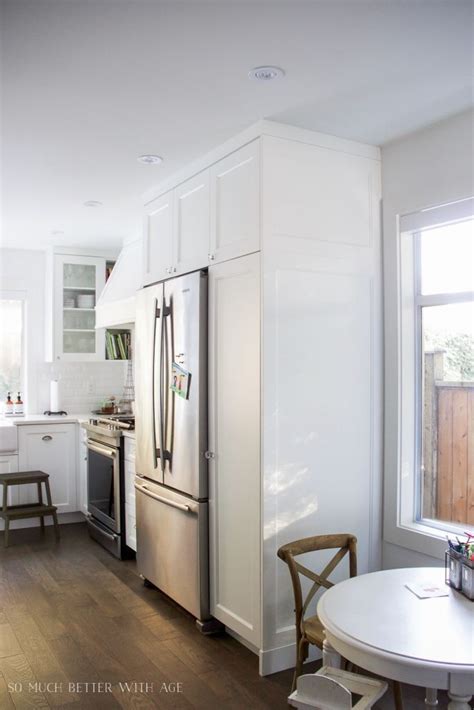 Built in refrigerator beside pantry loaded with pull outs. Pantry beside fridge; Built-in refrigerator, white kitchen ...