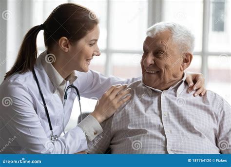 Female Caregiver Doctor Supporting Smiling Older Man Touching