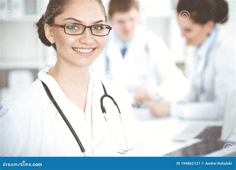 happy smiling woman doctor sitting and looking at camera at meeting with medical staff