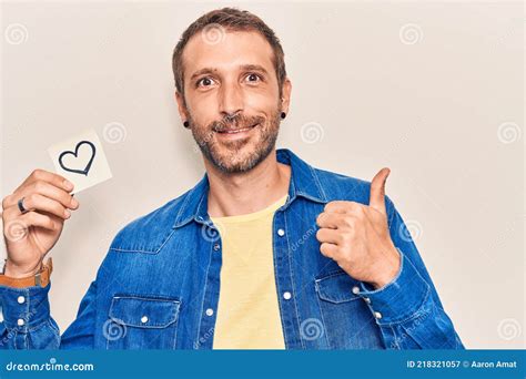 Young Handsome Man Holding Heart Reminder Smiling Happy And Positive Thumb Up Doing Excellent