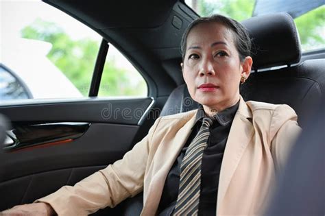 portrait of a successful aged asian businesswoman sitting on the car`s backseat stock image