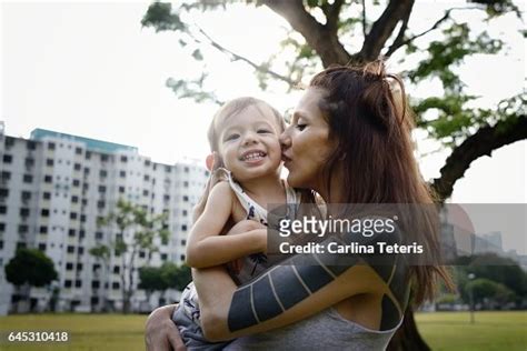 Tattoed Mom Holding Her Toddler Son In A Park High Res Stock Photo
