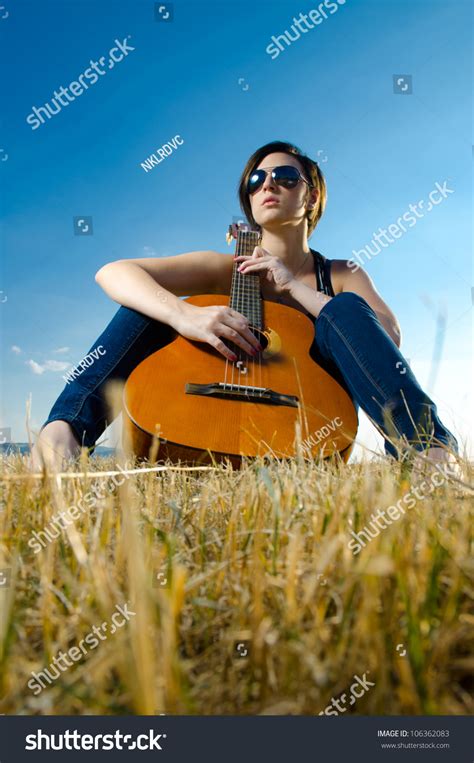 Beautiful Female Guitarist Wearing Sunglasses Sitting And Playing