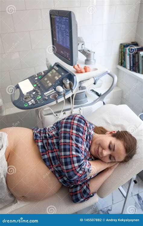 Happy Pregnant Woman Before Getting Ultrasound Scan From Obstetrician In Clinic Lying Lateral