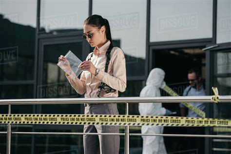 Female Detective Standing And Looking At Evidence In Package Stock