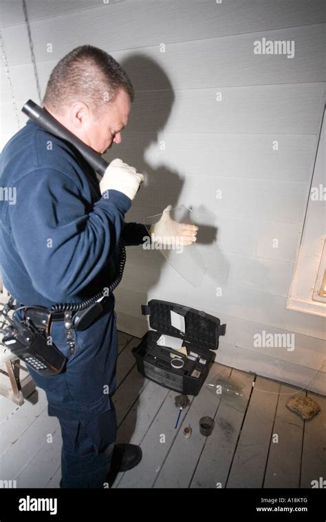 crime scene technician and detective inspects broken window at the scene of a burglary kansas