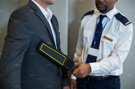 Airport Security Officer Using A Hand Held Metal Detector To Check A