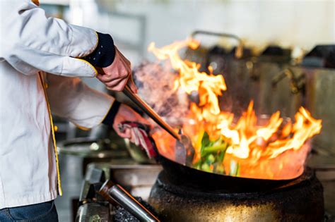 Chef Cooking With Flame In A Frying Pan On A Kitchen Stove Stock Photo