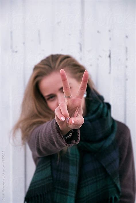 cheerful blonde girl showing peace sign at camera by stocksy contributor danil nevsky