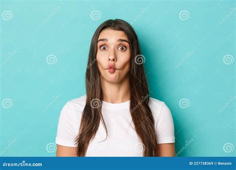 close up of silly brunette woman sucking lips and showing funny faces standing over blue