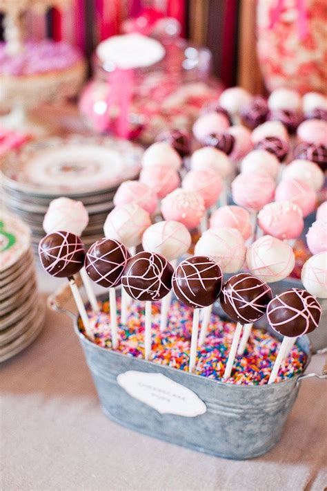 A Table Topped With Lots Of Candy Covered Lollipops Next To Other Desserts