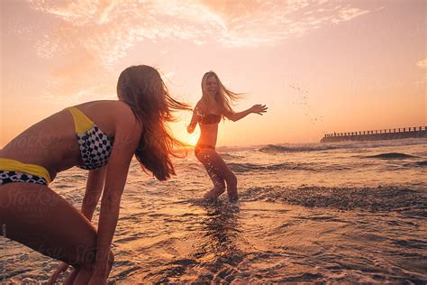 Friends Having Fun Swimming In The Sea At Sunrise By Stocksy